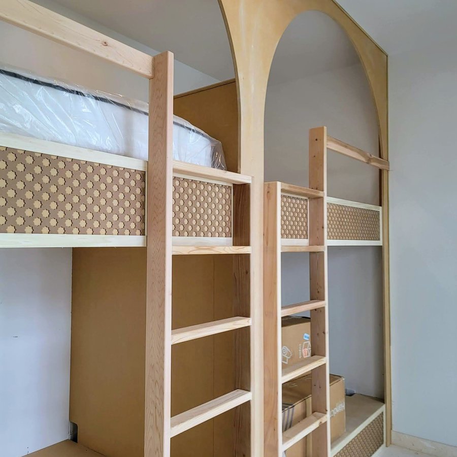 Custom bunk room built-in with an arched wood surround and ladder